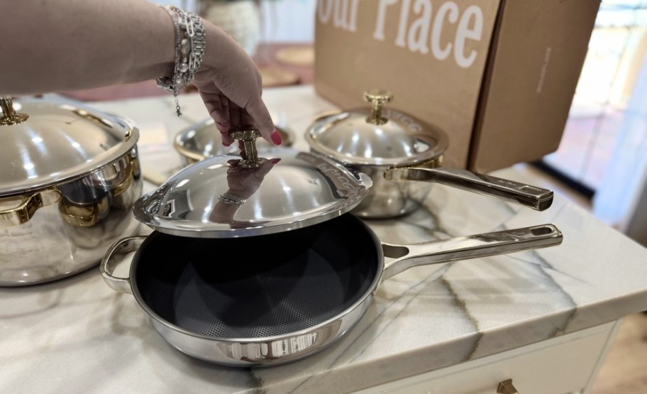 a womans hand lifting the lid of a fry pan 