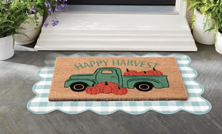 a pumpkin pickup truck welcome mat in front of a door