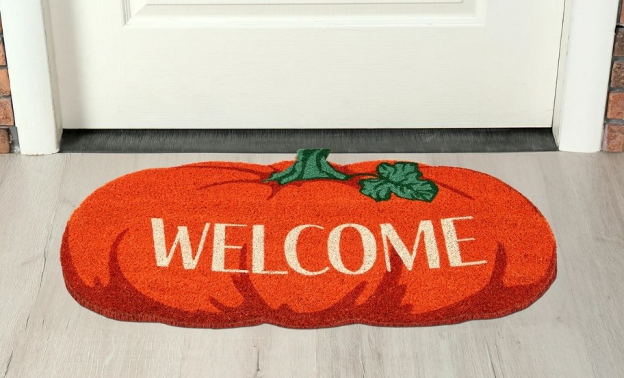a pumpkin welcome mat in front of a door