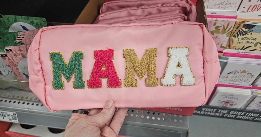 pink Way To Celebrate Mama Pouch with green, pink, gold, and white lettering on it in hand in store