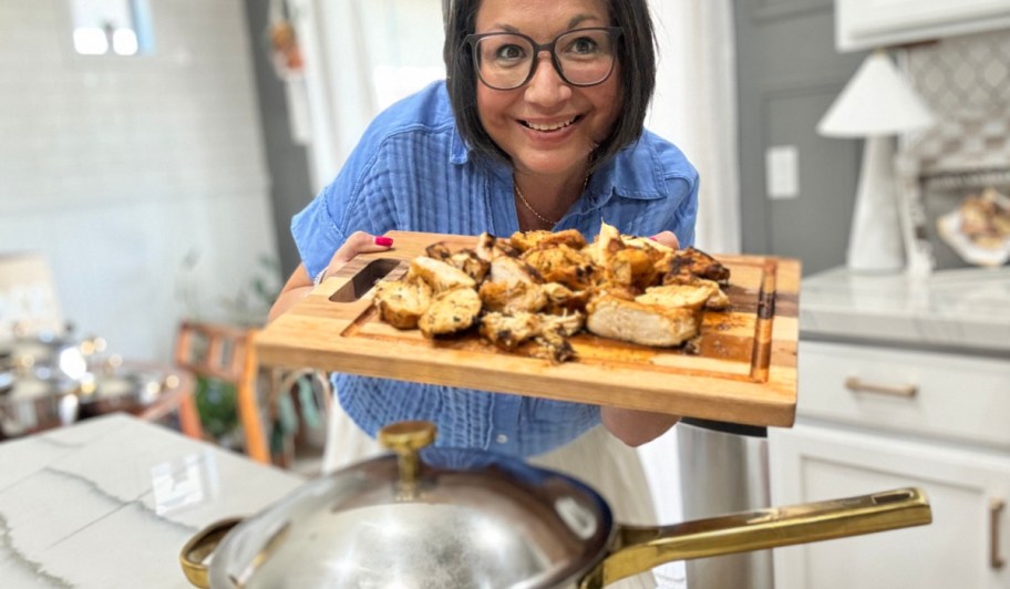 woman holding a cutting board with chicken 