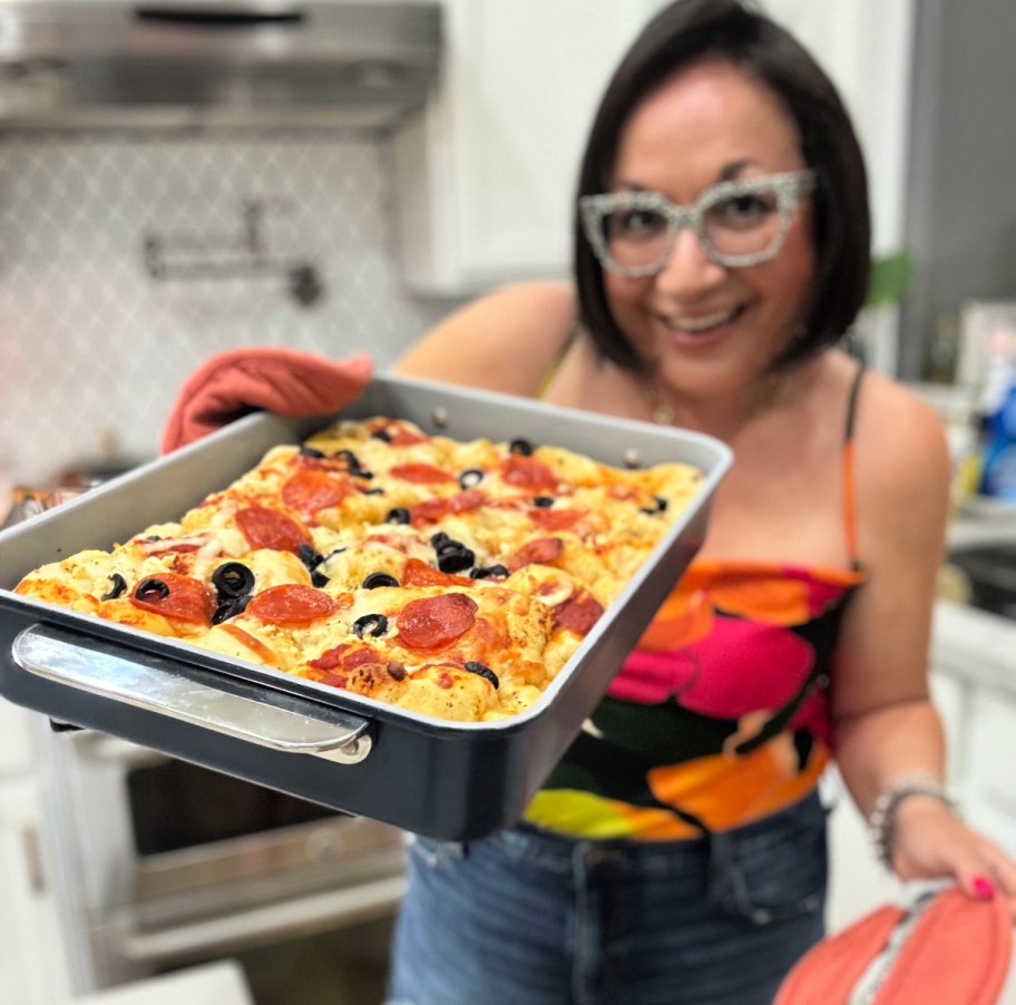 woman holding a tray of pizza focaccia bread