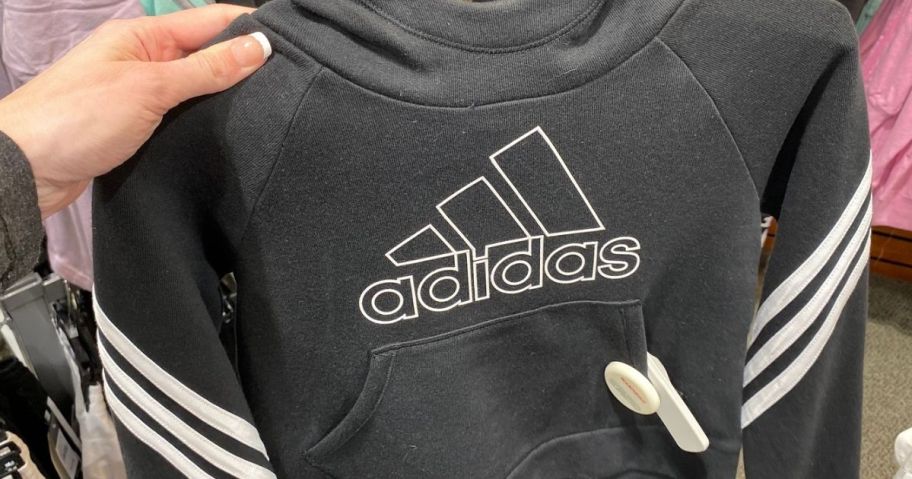 Hand holding an adidas sweatshirt