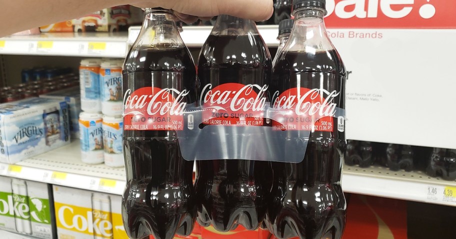 hand holding up a 6-pack of coke zero bottles