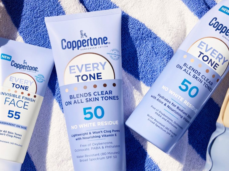 purple bottles of Coppertone Every Tone Sunscreen on striped beach towel