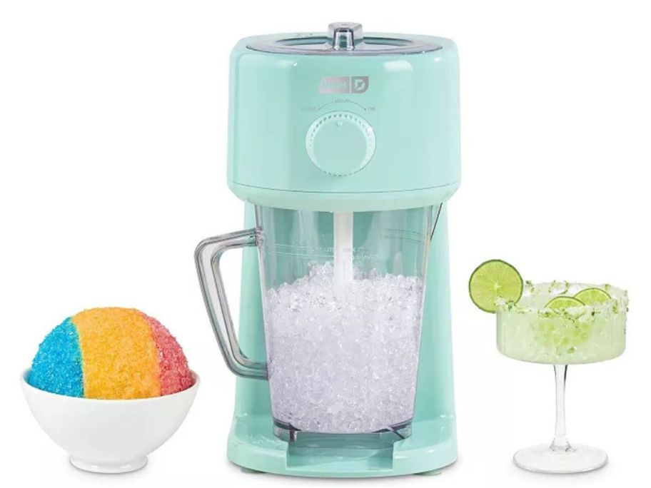 A slushy maker with shaved ice and a margarita next to it. 