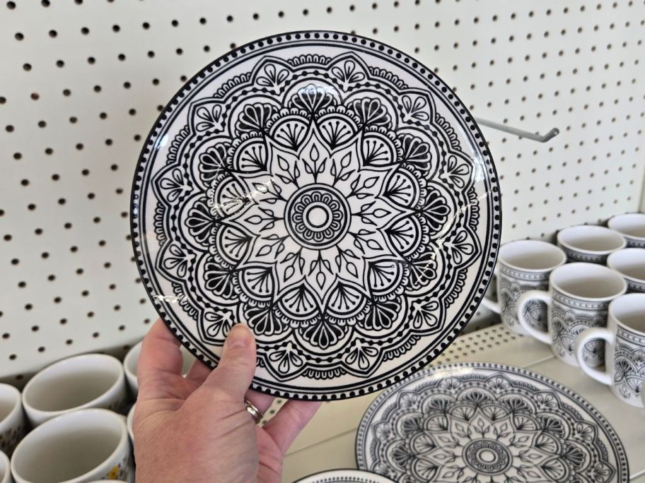 A person holding a black and white geometric patterned plate