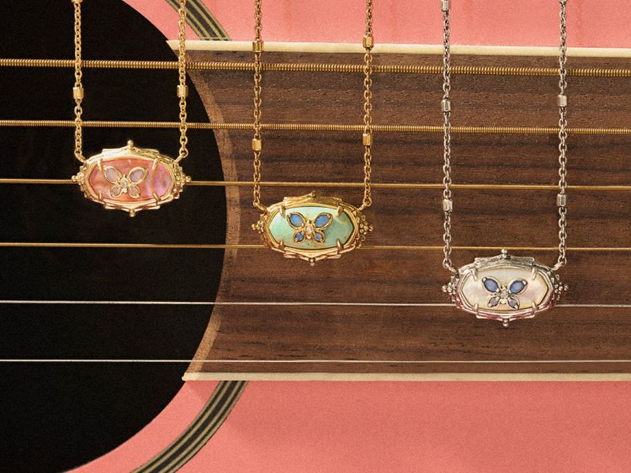 3 butterfly necklaces dangled in font of a pink guitar 