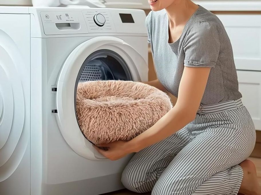 Woman putting a donut dog bed in a washing machine