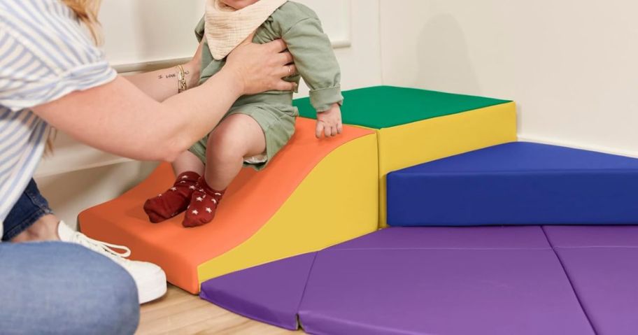 A child and a women playing on a small padded climber set
