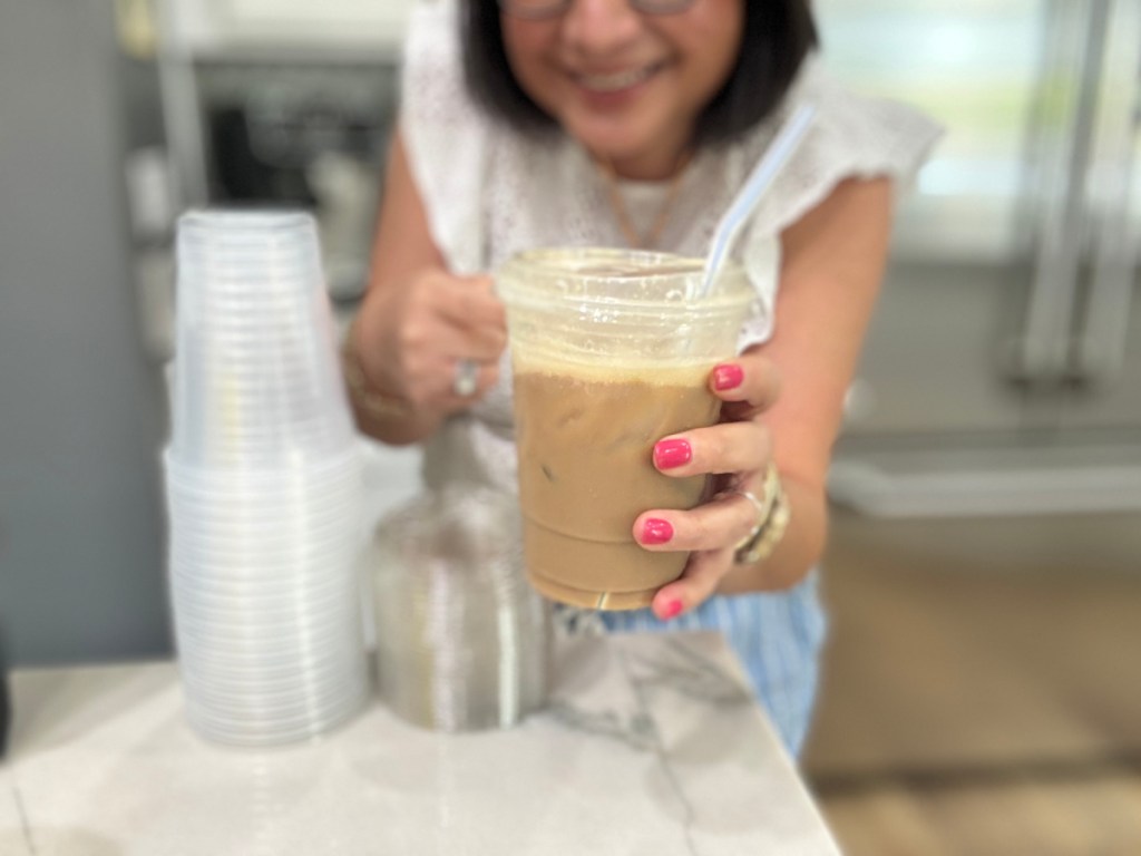 Woman holding out plastic great value sip cup, filled with coffee