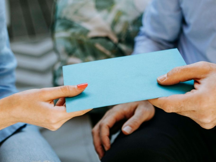 Man handing woman a greeting card in an envelope