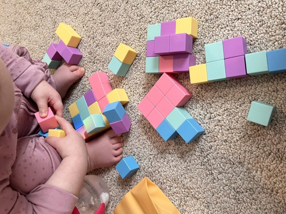 child playing with a set of pastel color magnetic blocks