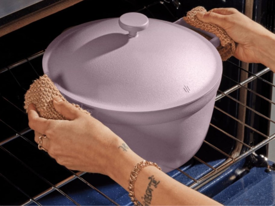 person's hands using pot holders, pulling a lavender 5.5 quart pot with lid out of the oven