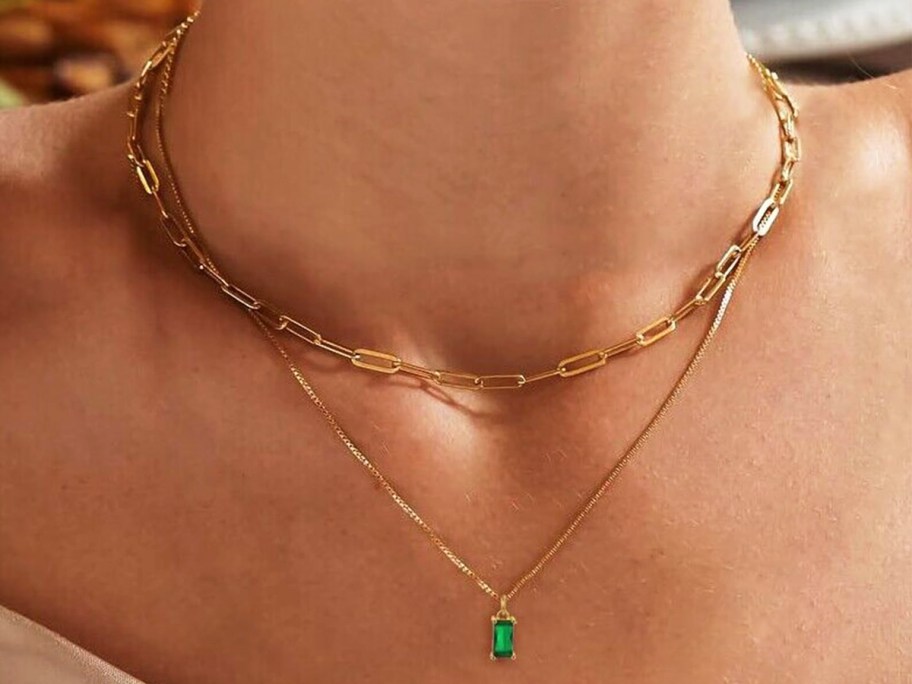 woman wearing a layered necklace with emerald pendant 