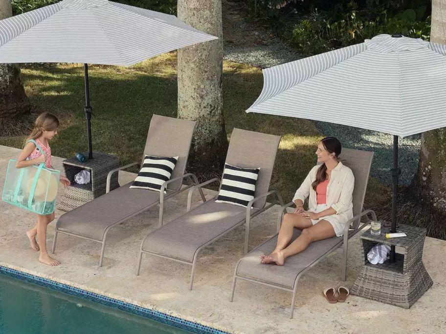 lounge chair with umbrellas and women with child sitting on them