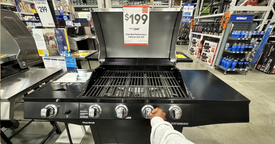 hand touching knob on Char-Broil grill on display in Lowe's store