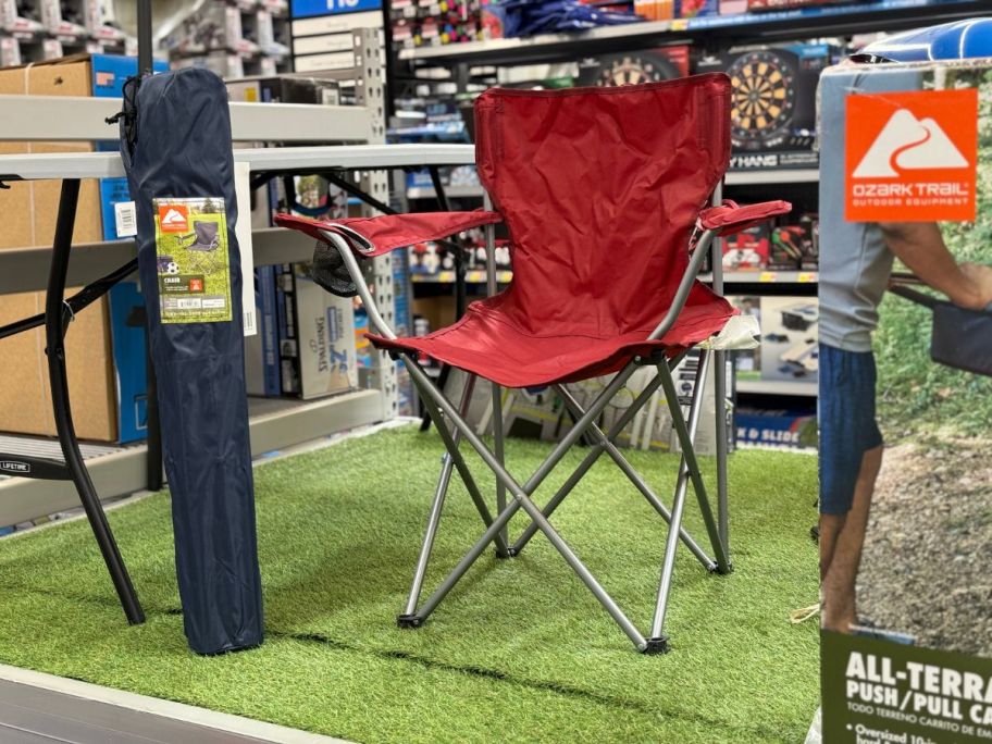 A red Ozark Trail Folding Camp Chair with Cup Holder displayed in a store