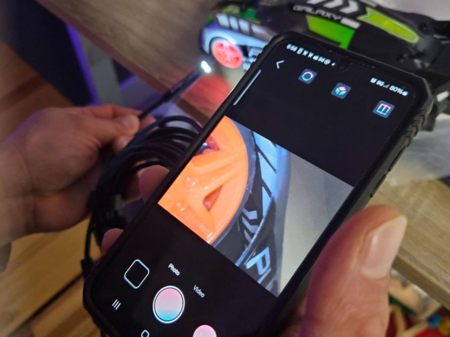 Hand holding a smart phone watching the camera footage from an endoscope