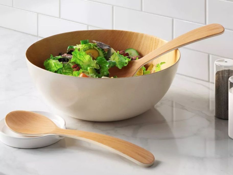 Serving bowl with salad inside and large spoon next to it