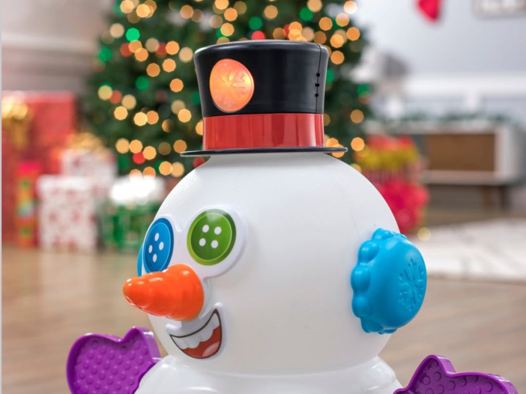 Plastic Mr. snowman toy with black and red hat in front of Christmas tree