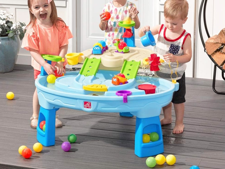 three kids playing with a blue water table on deck