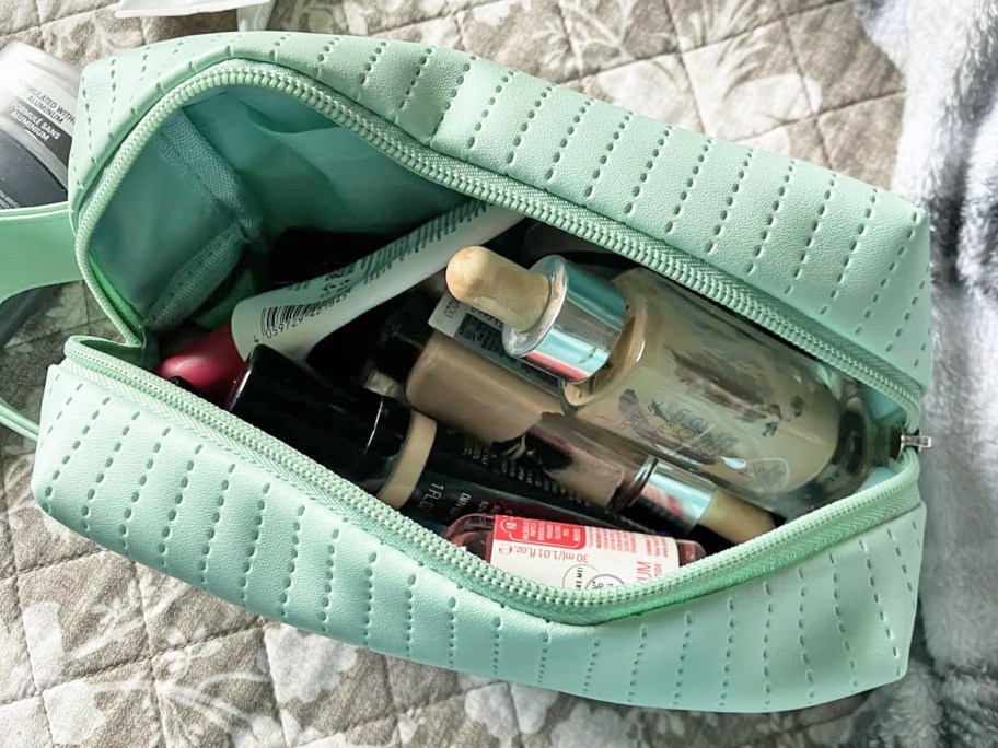 opened green cosmetic bag with makeup inside