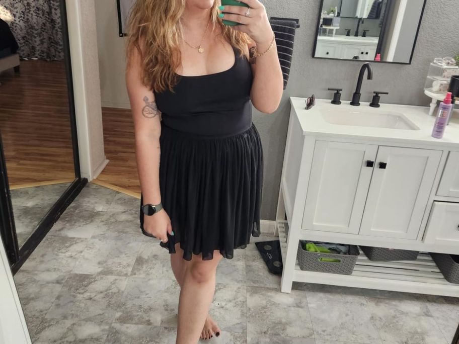 woman in black tennis dress taking picture of herself in the mirror