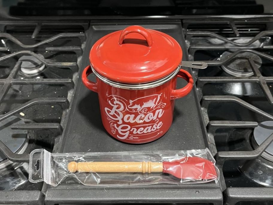 a red enamel farmhouse style bacon grease strainer sitting on top of a stove