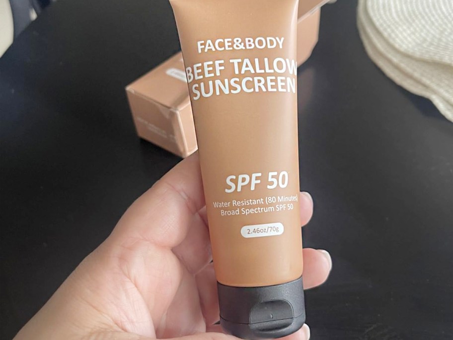 hand holding beef tallow sunscreen bottle