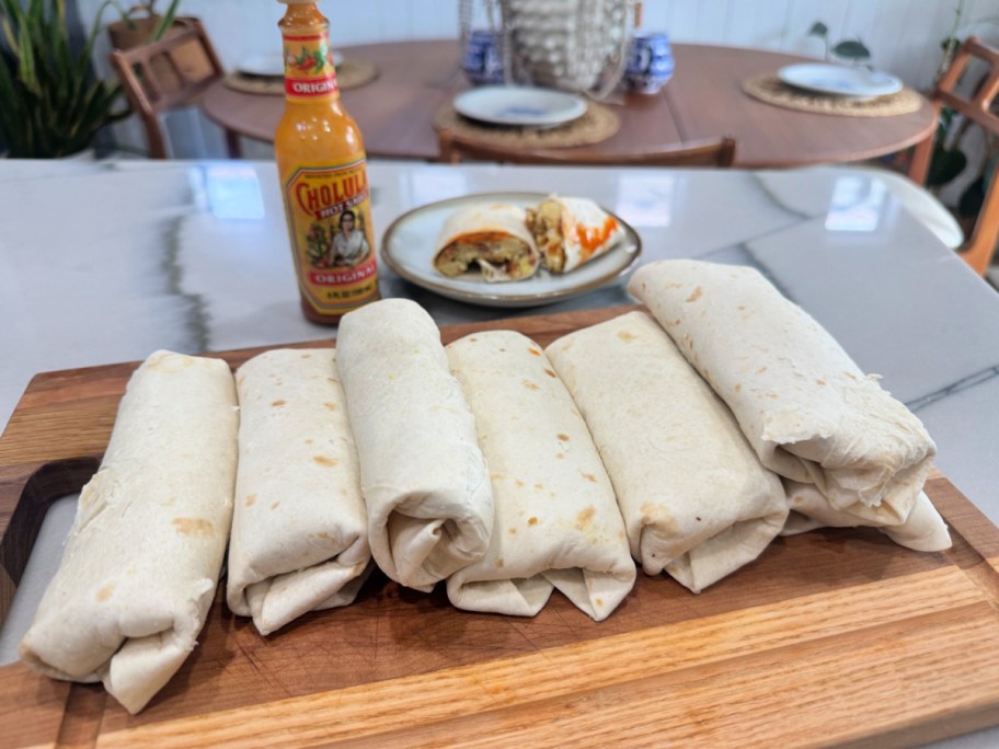 breakfast burritos on a cutting board rolled up 