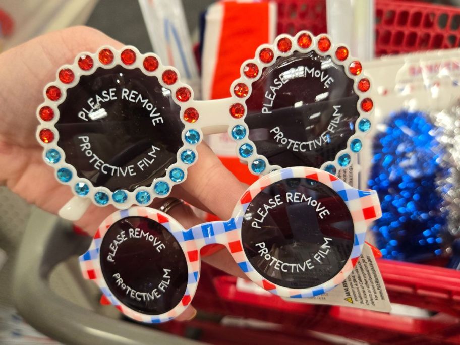 two red, white, and blue sunglasses in hand in store