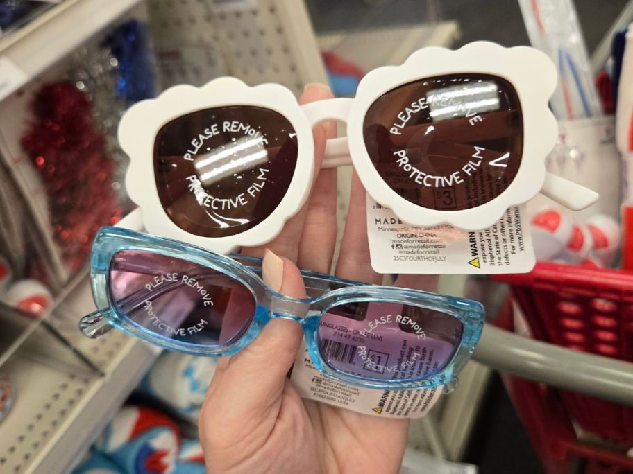 white and blue sunglasses in hand in store