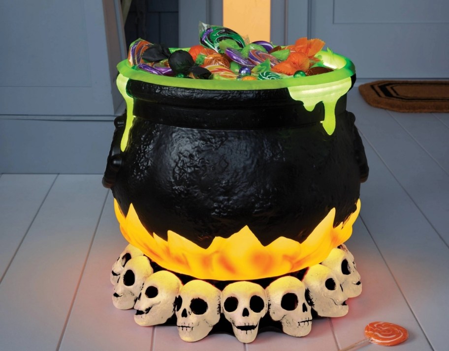 a light and sound halloween cauldron on a porch and filled with candy