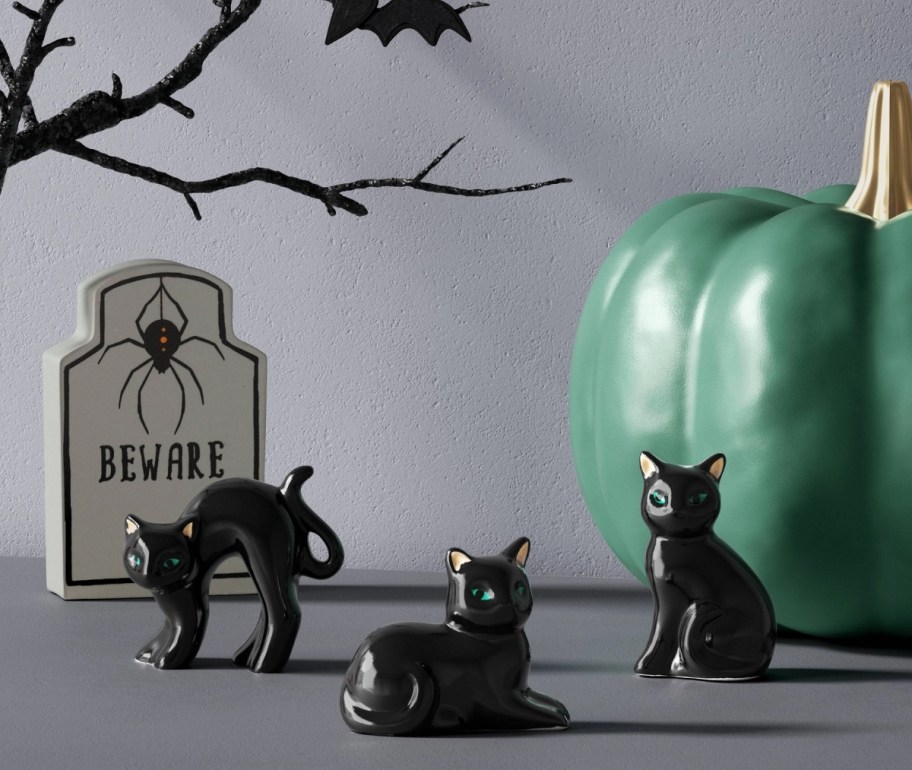  3 black cat figurines on a mantle