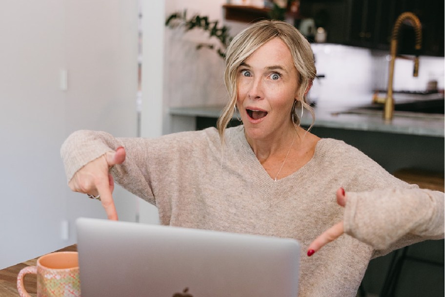 woman pointing at macbook laptop with excited expression