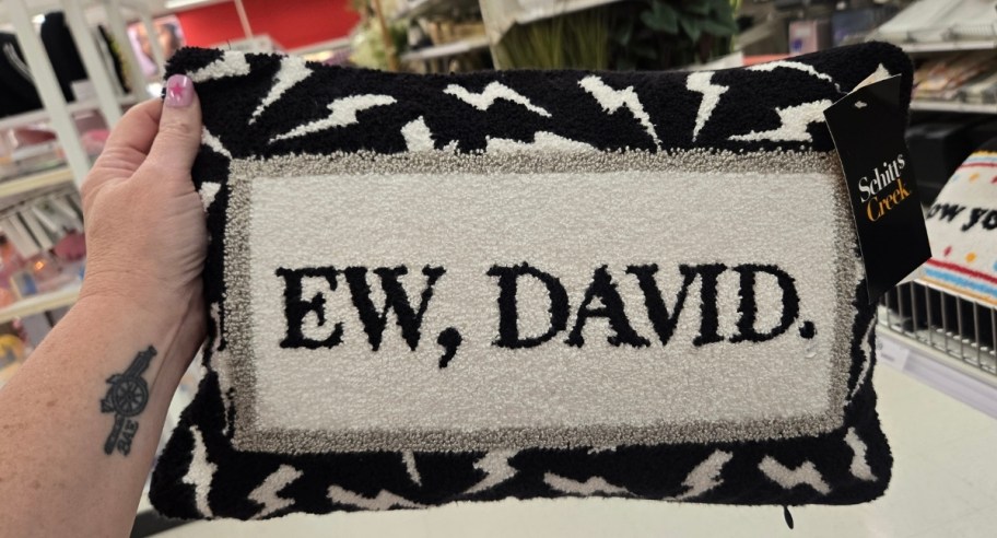 a womans hand holding a pillow that reads 'ew david.'