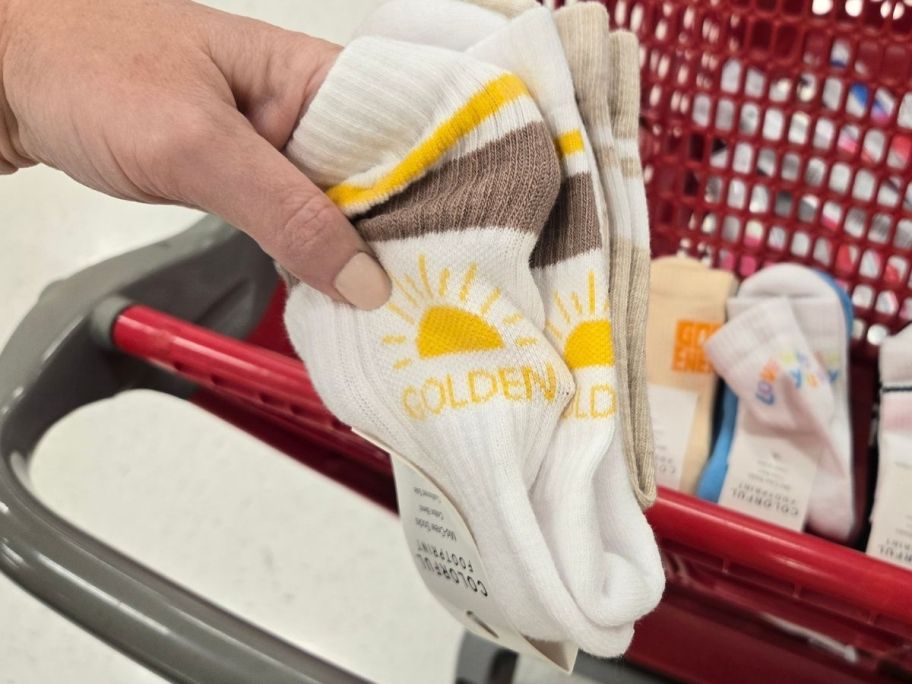 a womans hand holding a 2-pack of graphic crew socks