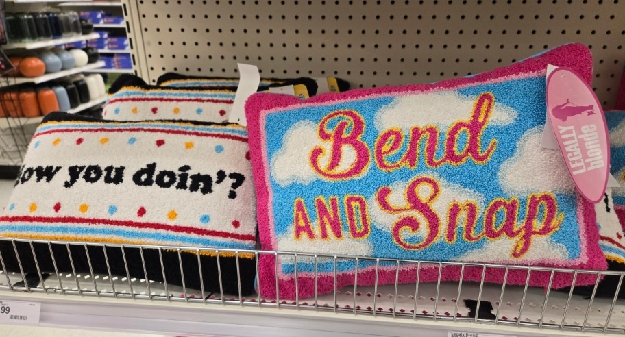 two novelty lumbar throw pillows on a store shelf