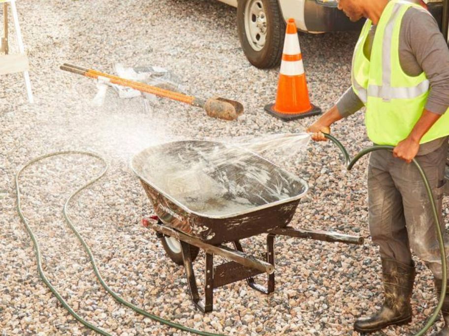 man using Husky 50' Heavy-Duty Hose on wheel barrow