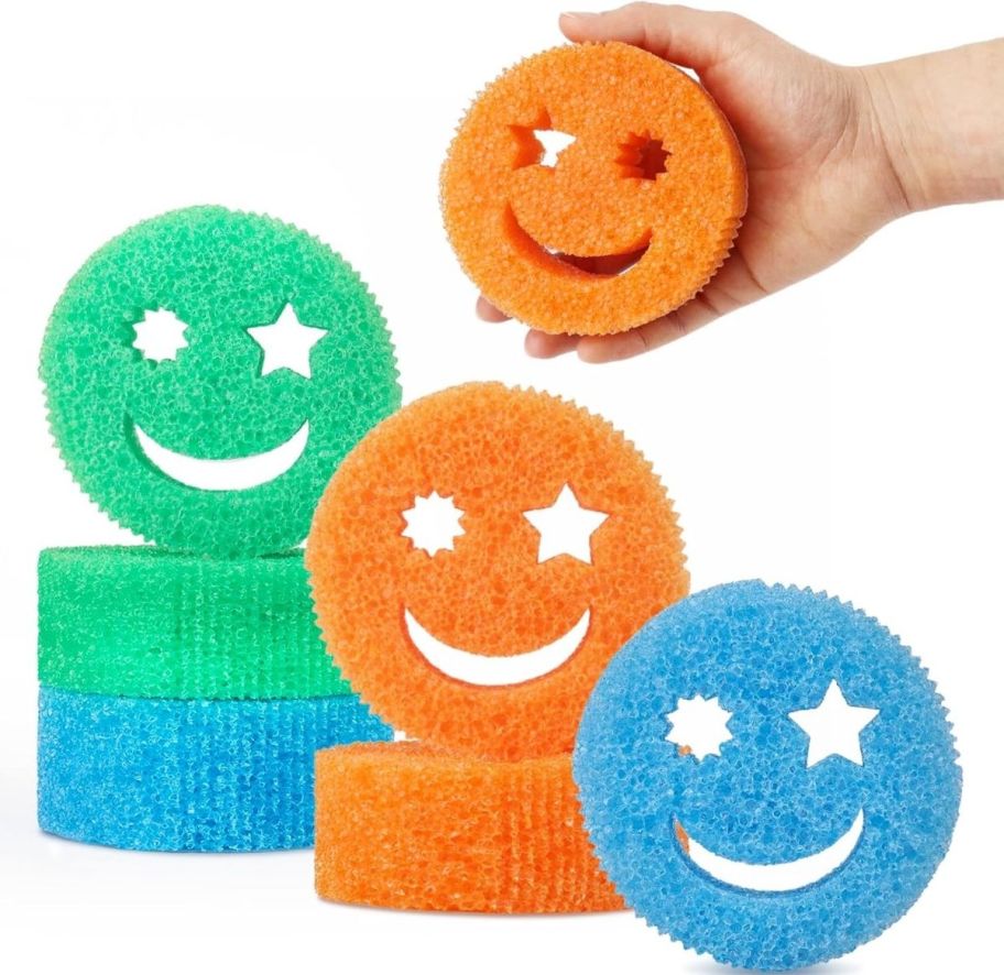 six smile sponges with 2 in each in orange, blue, and green and a mans hand holding an orange sponge