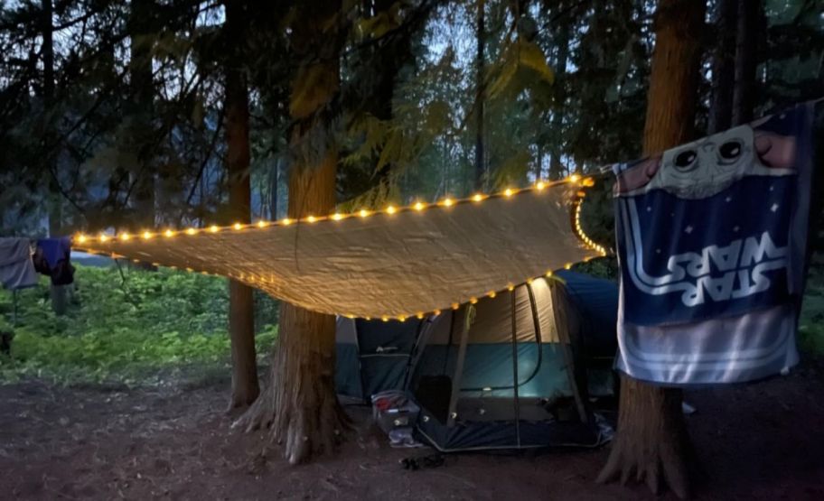an led shade sail installed in front of a tent at a camp site