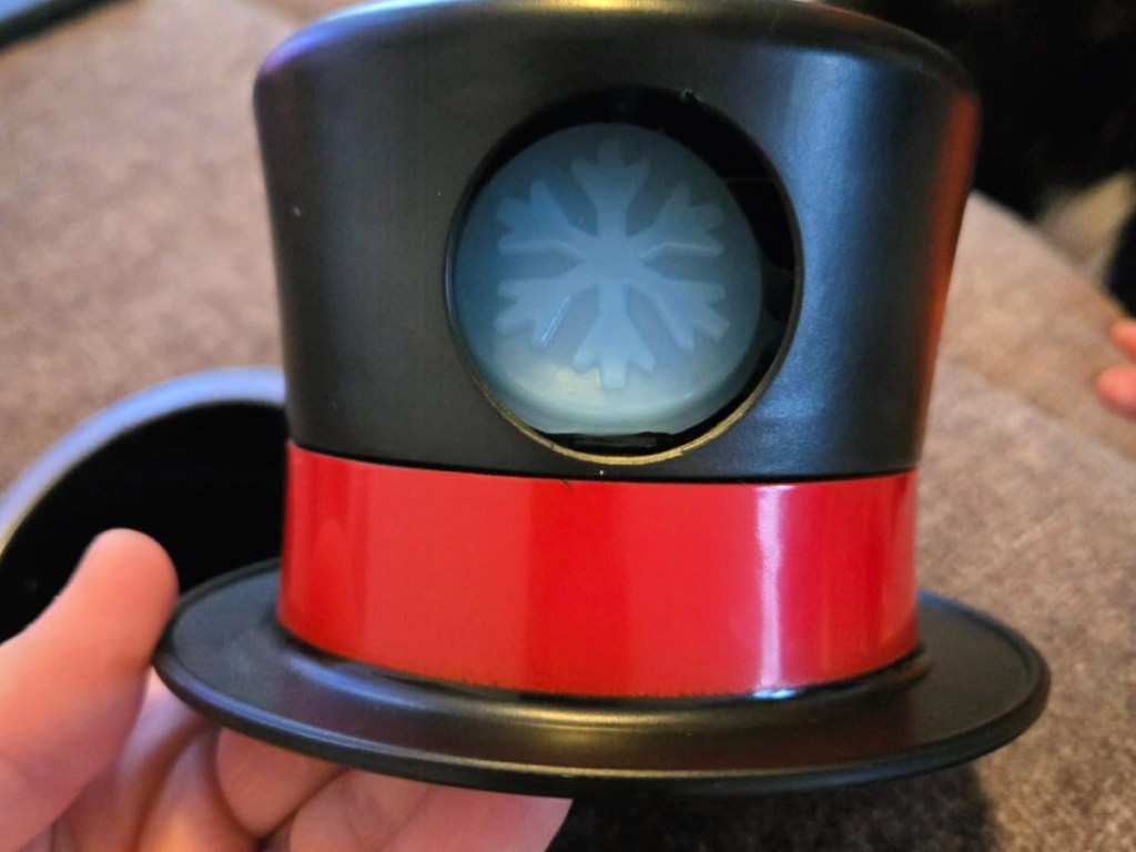 Person holding black and red my first snowman hat