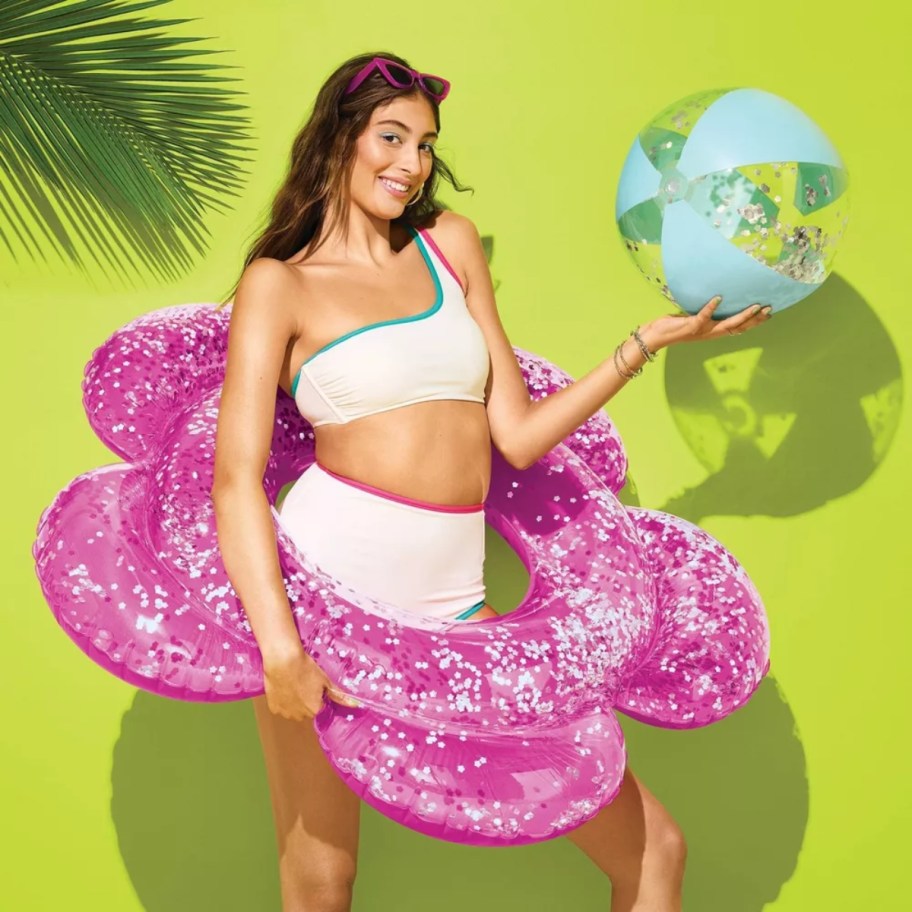 woman in a swimsuit with a flower pool tube and beach ball