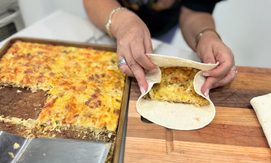 woman folding up breakfast burritos