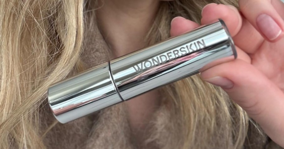 person holding a tube of wonderskin lip oil