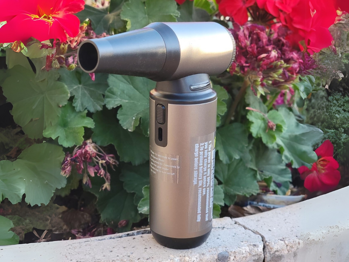 an air duster tool sitting outside by some flowers