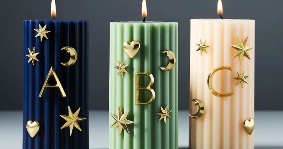 3 pillar candles with Anthropologie Candle Charms on them