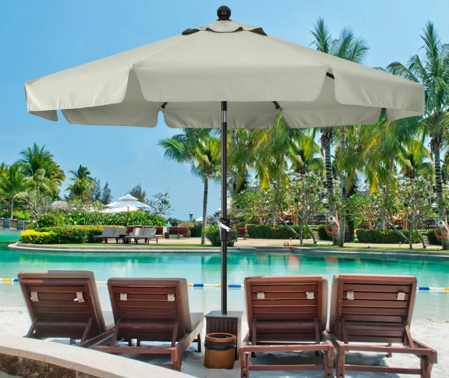 large light grey patio umbrella over 4 wood chairs on beach