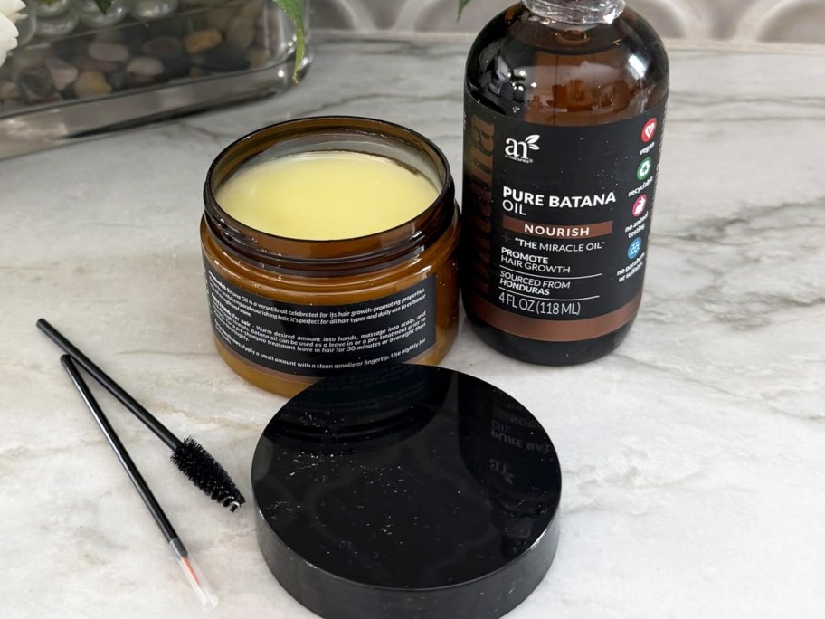 hair growth kit with oil serum and paste jars with brushes on marble table